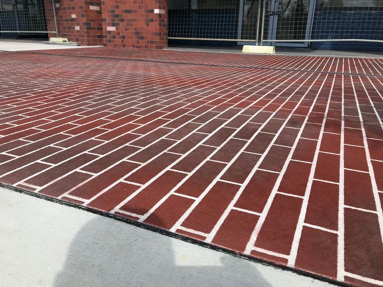 Red brick-pattern stencil spray-on concrete outside a building