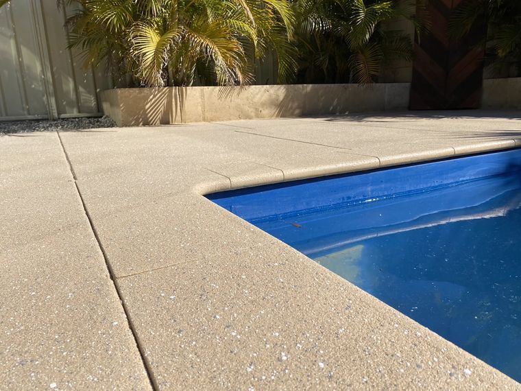 Light aggregate-look spray-on coping around a pool