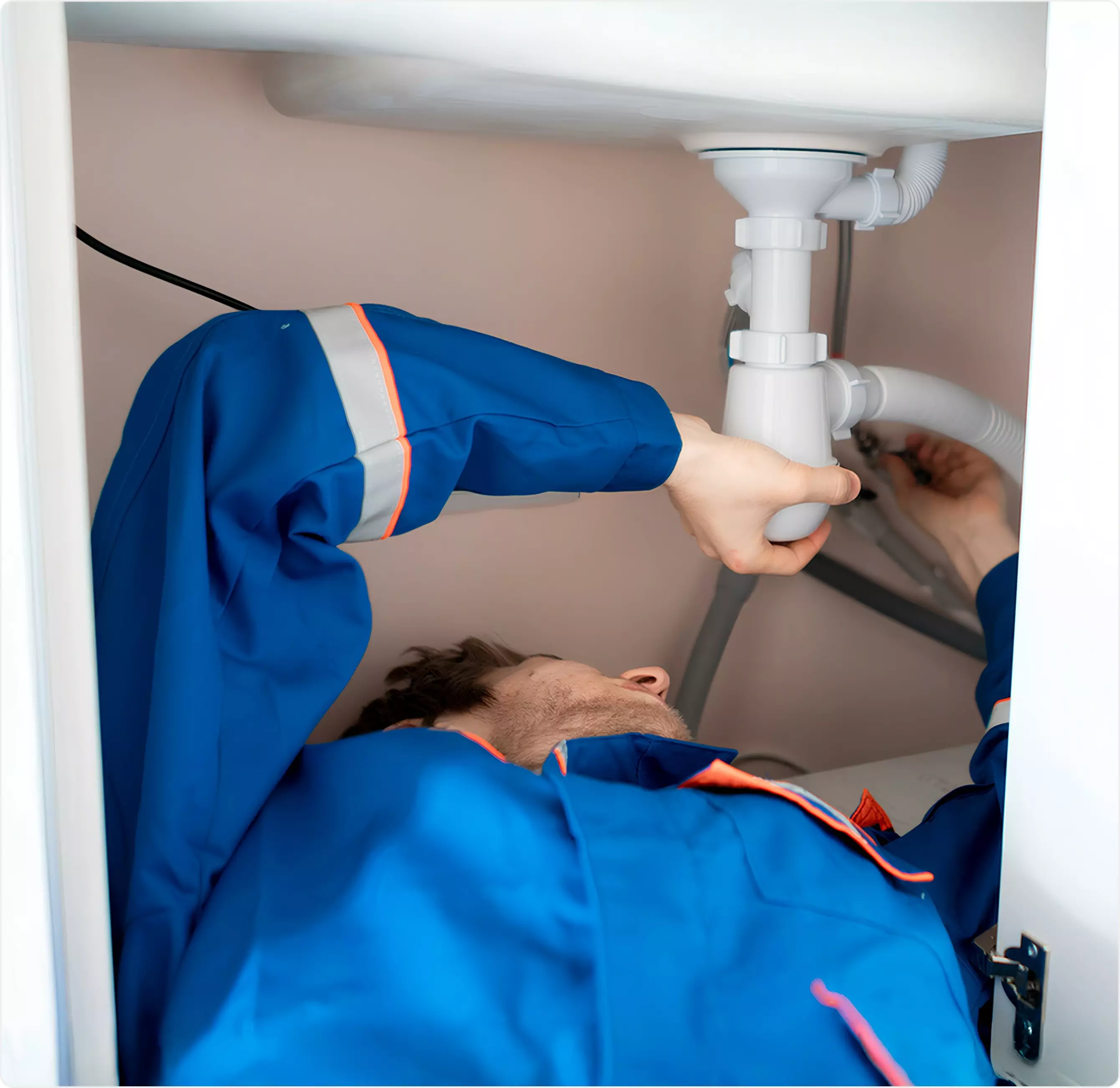 Plumber repairing a leak under a sink